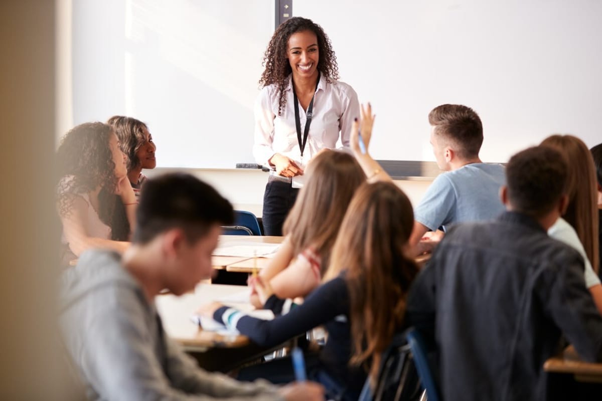 A smiling teacher interacting with a classroom filled with students